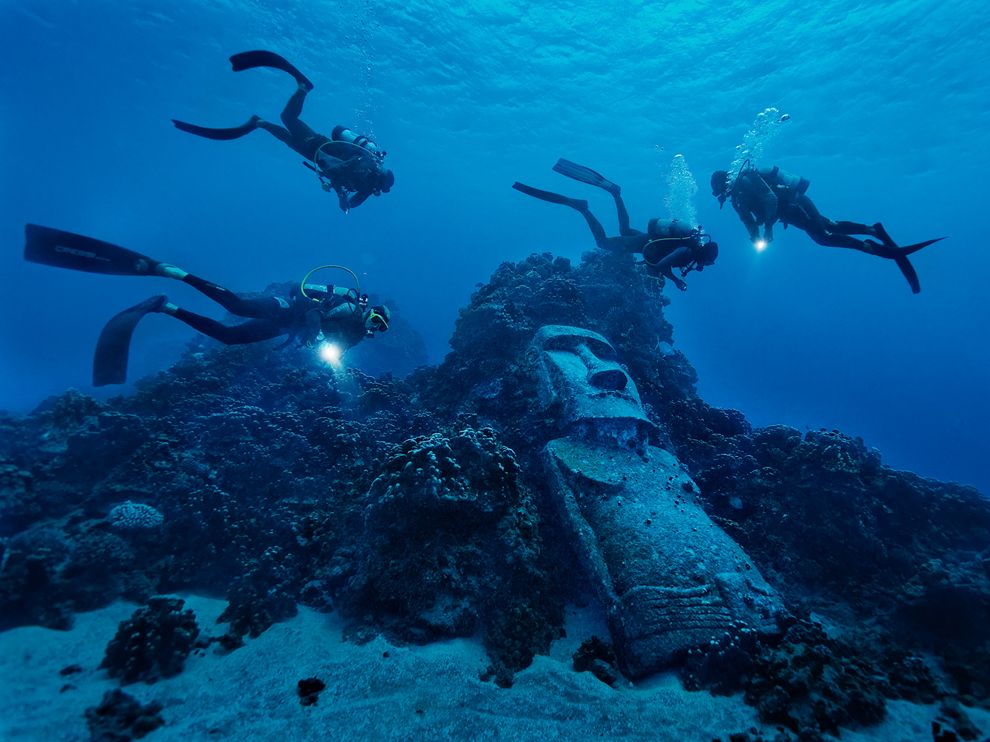 Picture of divers exploring a reef with fake moai off of Easter Island
