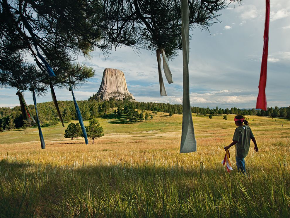Picture of a young boy placing prayer flags in a tree in Wyoming